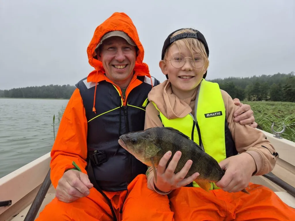 A man and a child sitting in a boat and holding a fish